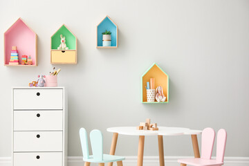 House shaped shelves and little table with chairs in children's room. Interior design