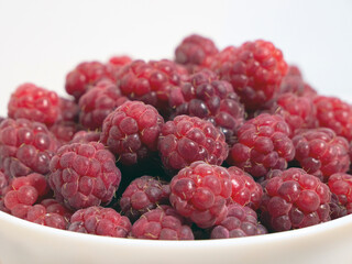 Close-up of fresh raspberries in a white plate. Toned raspberry background.