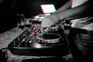 hands on DJ playing music on professional mixer controller in nightclub