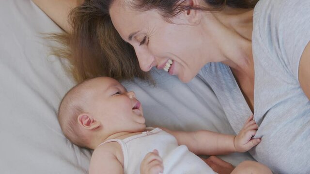 Close up mother kissing happy baby laughing enjoying loving mom nurturing toddler at home.