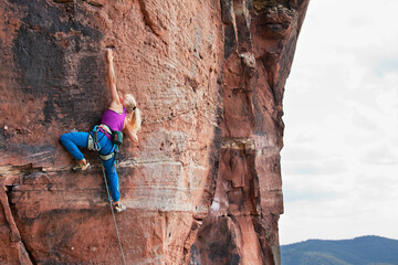 Young blonde woman climbing an extreme diffcult rock