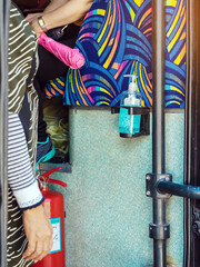 Blue alcohol gel bottle hanging on the door of the double-decker bus to serve passengers and prevent the spread of Corona Virus (Covid-19). Travel safely on public transport. New normal lifestyle.