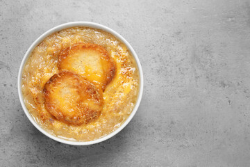 Tasty homemade french onion soup on grey table, top view. Space for text