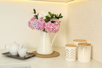 Beautiful bouquet of hydrangea flowers and tea on light countertop