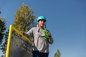 roller boy drinking water in a bottle in a skate park