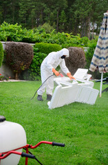 man with protection against covid 19 disinfects the garden by spraying with disinfectant product spraying product