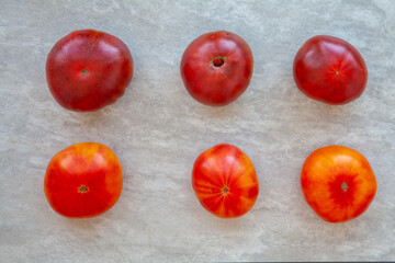 Six tomatoes of two different heirlooms. Top view, tomato bottoms comparison. Gray background.