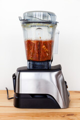 Blender with partly done tomato sauce from fresh tomatoes and other vegetable ingredients. Fast home cooking.