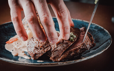chef hand cut Grilled beef steak filet mignon in plate on wooden table