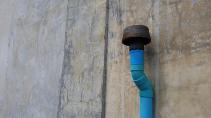 Old ventilation pipes on a cement wall. Blue PVC pipes are installed on the side of the cement wall of the house. For ventilation from the septic tank of the bathroom with a copy area. Selective focus