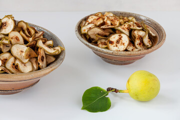 Dried healthy homemade fruit snacks in two bowls: one with spices and another without. Asian Pear dehydration, whole fruit in front.