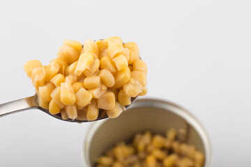Open metallic can with sweet corn on a white background.