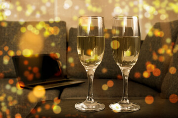 Two glasses of champagne with golden confetti, glitter, serpentine and lights. Night of celebration concept