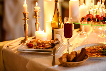 Fototapeta na wymiar Romantic luxury dinner for lovers indoor. Tasty dishes. New year, valentine day or anniversary. Burning candles on the table