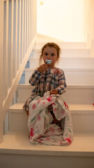 Lovely baby girl sitting in the white stairs