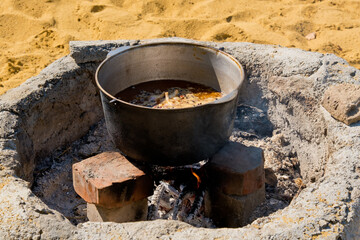 Cooking pilaf in a large cauldron over an open fire. Close-up.