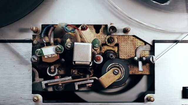 old and vintage bobbin tape recorder mechanism rewinding. audio head close up, grunge atmosphere top view