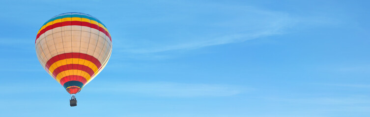 Fototapeta premium Hot air balloon in blue sky, space for text. Banner design
