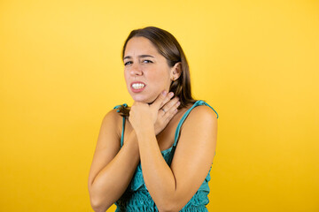 Young beautiful woman over isolated yellow background touching painful neck, sore throat for flu, clod and infection