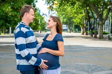 Happy family walking together. Pregnant mother and father spend time on city street.