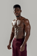 Fototapeta na wymiar Healthy body. Muscular african american man looking at camera, showing his naked torso while posing shirtless isolated over grey background. Sports, workout, bodybuilding concept