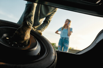 Close up of male hands taking out spare wheel, Man going to change car wheel while helping young...