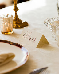Wedding place setting on textured tablecloth in warm light with name
