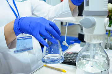 Lab assistant hands working with titrator to measure quality of drinking water