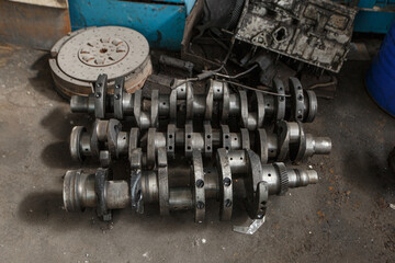 The crankshaft of an old truck lies on the floor. Foreground sharpness