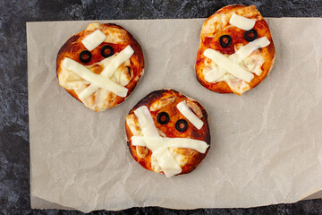 Mini pizza as mummy for kids with cheese, olives and ketchup. Funny crazy Halloween food for...