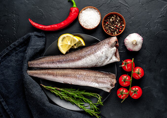 
raw fish hake with spices on a stone background