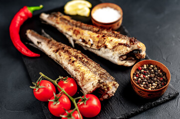 fried hake fish with spices on a stone background