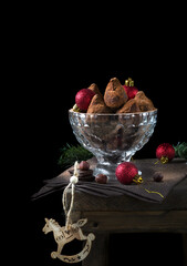 Chocolate truffles covered in cacao powder and red baubles against the black background. Christmas dessert