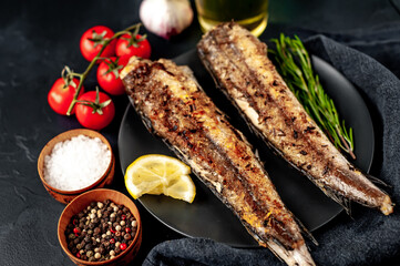 fried hake fish with spices on a stone background