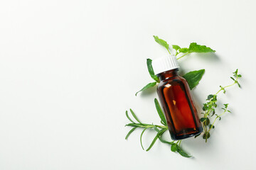 Medical bottle and herbs on white background, space for text