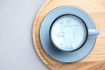 Blue matcha latte in cup on grey table, top view