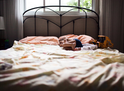 boy sleeping on a bed with toy truck