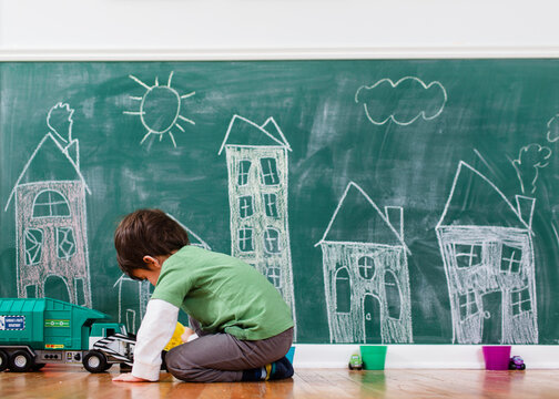boy plays in front of chalkboard city