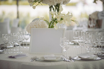 Wedding. Banquet. The chairs and round table for guests, served with cutlery, flowers and crockery and covered with a tablecloth.Elegant tablescape. White dinner table decorated with white flowers.