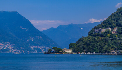Panoramic view of Lake Como, Italy with water plane flying, fountain, boats, and towns