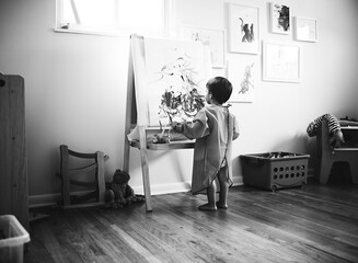 black and white photo of boy drawing at easel