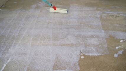 Priming the concrete floor with a roller. Professional floor primer. Leveling concrete floors....