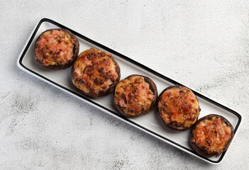Champignons stuffed with ham and cheese on a rectangular on a light gray background. Top view, flat lay