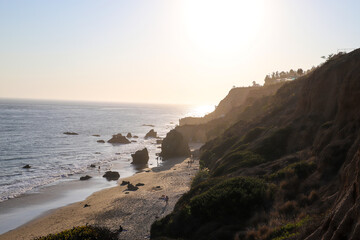 people playing on the beach at sunset with deep blue ocean water and waves rolling in  at El...