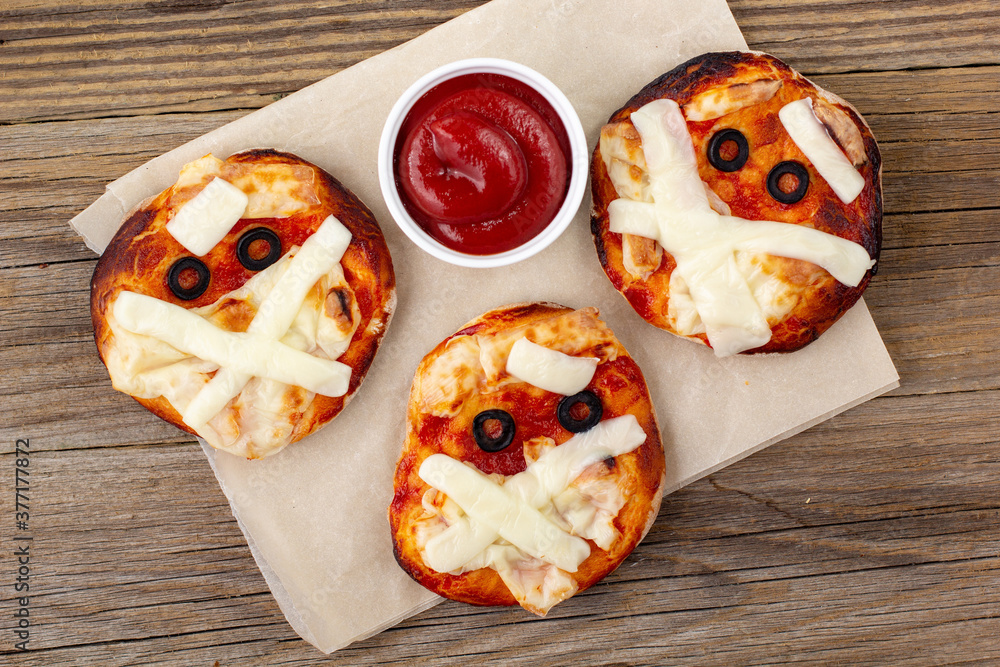 Poster Mini pizza as mummy for kids with cheese, olives and ketchup. Funny crazy Halloween food for children