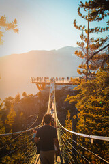Naklejka premium People walk along a suspension bridge during sunset