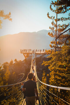 People walk along a suspension bridge during sunset