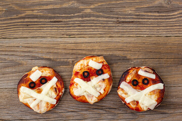 Mini pizza as mummy for kids with cheese, olives and ketchup. Funny crazy Halloween food for...