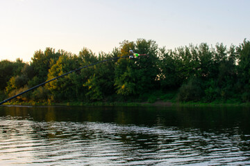 Fototapeta na wymiar Feeder fishing rod on the sunset background the lake. Carp fishing rod on river. 
