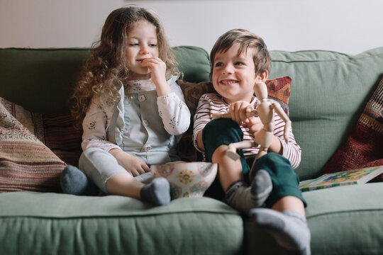 Young cute kids playing with mannequin on the couch